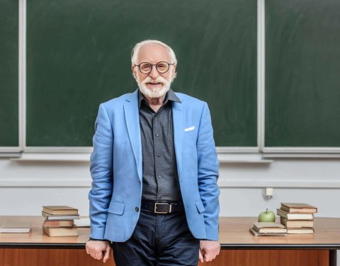 smiling-grey-hair-professor-standing-in-lecture-ro-2022-12-16-17-25-04-utc.jpg